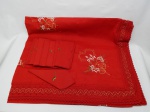 CAMA E MESA, nove (09) peças: uma toalha de mesa confeccionada em tecido de algodão na tonalidade vermelha, ornada com bordado de motivos natalinos, barrado de crochê de linha vermelha e fios metalizados, acompanha oito guardanapos fazendo jogo; usados.