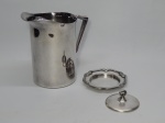 METAL PRATEADO, dois (2) itens: 1 refresqueira, cilíndrica, com retentor de gelo, alças relevadas em volutas, manufatura BELPRATA, medindo 18,5 cm altura; 1 tampa e presentoir de manteigueira, falta o recipiente em vidro, ornamentação em frisos, terminando em laçarotes, manufatura FRACALANZA (tradição desde 1884), medindo 11,5 cm diâmetro.