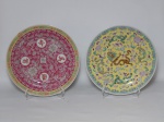 PORCELANA CHINESA, dois (2) pratos decorativos: 1 com ornamentação floral e geométrica em policromia, barrado grego, fundo com predominância da tonalidade magenta, possui quatro ideogramas em caracteres: WAN, SHOU, WU e JIANG (os 4 juntos significam vida eterna, geralmente utilizados em porcelanas contemporâneas e popularmente conhecido como padrão aniversário, somente uma vez este padrão serviu para decorar uma porcelana antiga no caso o serviço do casamento do imperador TONGZHI em 1872, o de época é sobre fundo amarelo), medindo 26,5 cm diâmetro; 1 com ornamentação policromada representando dragões celestiais sobre fundo na tonalidade amarela, medindo 26 cm diâmetro, ambos com marca de origem na tonalidade vermelha em legenda e caracteres.