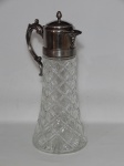 VIDRO, um (1) Decanter, incolor e translúcido, moldado em geométricos, com monture em metal prateado com pega da tampa na forma de pinha, alça e bico com ornamentação relevada em volutas e elementos vegetalistas, medindo 35 cm altura, possui porta gelo em polímero no interior, usado.