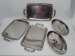 AÇO INOX E METAL PRATEADO, cinco (5) itens: 2 travessas ovais fundas, marca KE HOME, medindo 30 cm comprimento, procedência R.P.C. (República Popular da China); 3 bandejas distintas retangulares, medindo a maior 44 x 26 cm, todas usadas, uma apresenta oxidação.