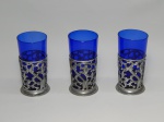 VIDRO E METAL PRATEADO, três (3) copos translúcidos na tonalidade azul cobalto, base metálica vazada, medindo 13 cm altura, usados.
