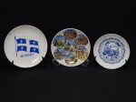 PORCELANA, três (3) pratos decorativos souvenir: 1 de Boston, Massachusetts, USA, com paisagem urbana, tonalidade azul sobre fundo branco, marca de origem China, medindo 17,5 cm diâmetro; 1 com bandeira de Quebec, Canadá, tonalidade azul sobre fundo branco, medindo 21 cm diâmetro; 1 de Roma, Itália, ornado com diversos pontos turísticos em policromia, marca de origem no verso PRODOTTO ITALIANO, medindo 19,5 cm diâmetro.