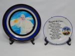 ARTE SACRA, dois (2) pratos em porcelana: 1 com o Papa Francisco ao lado da bandeira da Argentina, borda com faixas nas tonalidades preta, azul, branca e dourada, legenda PAPA FRANCISCO  ARGENTINA, medindo 25 cm diâmetro; 1 Lembrança do Convento da Penha, Vila Velha, Espirito Santo, Brasil, manufatura SCHMIDT (Pomerode, SC; Mauá, SP; Campo Largo, PR, fundada em 1945, ainda em atividade, maior fábrica de porcelana da América Latina), medindo 19 cm diâmetro.