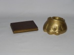 BRONZE E LATÃO, dois (2) itens: 1 cinzeiro no formato de pata de elefante, medindo 12,5 cm diâmetro; 1 porta charutos com ornamentação floral relevada no padrão Art Nouveau, tampa com abertura basculante, interior com forração em couro, marcado com as iniciais MC, medindo 13,5 x 9,5 x 2 cm.