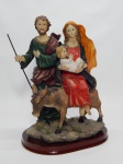 ARTE SACRA, uma (1) escultura policromada retratando a fuga da Sagrada Família para o Egito, Menino Jesus, Maria e José em um burrico, confeccionada em poliéster, possivelmente italiana, medindo 26 cm altura.