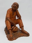 ESCULTURA, uma (1) representando homem sentado com chapéu na mão, confeccionada em cerâmica, assinatura não identificada, medindo 23 cm altura.
