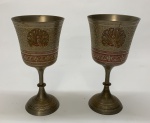 METAL PRATEADO, par (2) taças de pé alto, ornamentação cinzelada em pavões e elementos vegetalistas, fuste com anel intermediário, base cônica, cinzelada com barrado geométrico, singela esmaltação na tonalidade vermelha, medindo 15,5 cm altura.