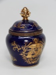 PORCELANA FRANCESA, um (1) potiche com tampa, ornamentação dourada com cenas palacianas e moldura em elementos vegetalistas, encimada por cabeça de medusa, pega da tampa em pinha, fundo azul cobalto, marca de origem LIMOGES, França, monture em bronze relevado em tracejados e perolados intercalados, terminação com botão floral, medindo 17,5 cm altura.