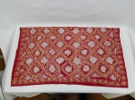 CAMA E MESA, uma (1) toalha no formato quase quadrangular, confeccionada em tecido na tonalidade vermelha com bordado floral em linha amarela e branca, medindo 98 x 84 cm, usada.