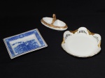 PORCELANA, três (3) itens: 1 covilhete retangular, ornado com paisagem do porto, tonalidade azul e branca, arremates em dourado, manufatura VISTA ALEGRE (fundada em 1824, pelo negociante, lavrador, industrial e político, José Ferreira Pinto Basto, através de alvará concedido por D. João VI, tendo seu fundador associado a fábrica os seus 15 filhos, ficando a sociedade denominada Ferreira Pinto & Filhos; cinco anos mais tarde recebe o título real pelo reconhecimento de sua arte e sucesso, ficando conhecida como Real Fábrica da Vista Alegre, começou no fabrico de vidros enquanto se empenhava em esforços para a produção de porcelana, os primeiros ensaios conseguidos foram imperfeitos denominado loiça de pó de pedra, através de boas relações com a fábrica francesa de Sevres conseguiu as receitas para o fabrico de porcelana, somente em 1832, por sorte, é encontrado um jazigo de caulim situado em Aveiro, próximo a Ílhavo, a partir desta data o fabrico de porcelana foi se aperfeiçoando em Portugal, 1851 expôs com sucesso no Palácio de Cristal em Londres; 1852 D. Fernando II visita a fábrica e encomenda uma baixela completa; 1867 recebeu sua primeira premiação na Exposição Universal de Paris; 1880 interrompe a produção de vidros para se dedicar exclusivamente a porcelana; 1964 inauguração do Museu Histórico da Vista Alegre; ainda em funcionamento), medindo 14 x 11 cm; 1 pequena fruteira na tonalidade branca com borda vazada e recortada, manufatura MAGHSOUD PORCELAIN (fundada em 1992/93 no Irã, ainda em fincionamento), medindo 16 cm diâmetro; 1 saleiro com divisória, tonalidade branca, detalhes texturizados como se fosse mármore, arremates em dourado, manufatura REAL (Mauá, SP, 1943 a 1994), medindo 12,5 x 6 x 7 cm.