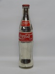 COLECIONISMO, uma (1) garrafa de Coca-Cola, lacrada e sem conteúdo, interior prateado, capacidade 290 ml, medindo 24,5 cm altura.