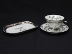 PORCELANA, dois (2) itens: 1 bandeja oval, ornamentação prateada com a legenda BODAS DE PRATA (25 anos) e faixas, manufatura PORCELANARTE (Campo Largo, PR, décadas de 60/70, empresa decoradora de porcelana), medindo 18,5 x 11,5 cm; 1 xícara para chá, ornamentação prateada com a legenda BODAS DE PRATA (25 anos), faixas, volutas e elementos vegetalistas, bicado na borda do pires, manufatura SCHMIDT (Pomerode, SC; Mauá, SP; Campo Largo, PR, fundada em 1945, ainda em atividade, maior fábrica de porcelana da América Latina).