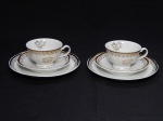 PORCELANA, dois (2) trios para chá (xícara, pires e prato de sobremesa), ornado com a legenda BODAS DE OURO (50 anos), arremates com barrado contínuo a ouro sobre fundo branco, manufatura GERMER (fundada em 1950 em Timbó, SC, como fabricante de acessórios para maquinário têxtil; em 1964 passou a produzir componentes para lançadeiras; em 1969 passou a produzir isoladores elétricos; em 1978 quando assumiu o controle da POLOVI Campo Largo, PR passou a produzir porcelana de mesa; em 1988 modernizou a fabrica com a aquisição de novos fornos, atualmente é a segunda maior produtora de porcelana do Brasil), possui bicados em um dos pires, medindo a maior peça 19 cm diâmetro.