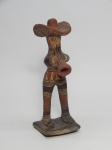 ARTE INDÍGENA, um (1) boneco, confeccionado em barro cozido, representando homem com chapéu tocando corneta, base tipo joão bobo (balança), possivelmente, pelas características, representação atípica de figura antropomorfa e mitológica da cerâmica RITXÒKÒ, arte e ofício, modelada pelas mulheres da tribo do povo KARAJÁ, localizados na região central do Brasil as margens do Rio Araguaia, Planalto Central e Serra do Caiapó, medindo 20 cm altura.