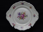 PORCELANA, um (1) prato de bolo, ornamentação floral policromada, arremates com frisos dourados, manufatura Carl Tielsch (fundada em 1845, na cidade de Altwasser, como Carl Tielsch & Co, no inicio suas peças eram marcadas com as letras TPM Tielsch-Porzellan-Manufaktur; em 1917 mudou para Carl Tielsch & Co. A. G.; em 1932 mudou para Porzellanfabrik Tielsch & Co, Abteilung der C. M. Hutschenreuther A. G.; em 1945 mudou para Polska Fabryka Porcelany Tielsch (território deixou de ser da Alemanha e passou a ser da Polônia); em 1952 mudou para Zaklady Porcelany Stolowej Walbrzych; a partir de 1992 acresceu no ultimo nome da fábrica as letras S.A. Funciona assim até a atualidade), medindo 27,5 x 25 cm.