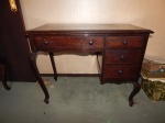 Mesa escrivaninha em madeira nobre, pernas arqueadas, 3 gavetas laterais e 1 central, puxadores de madeira torneada. Primeiro quartel do século XX. Pequenos restauros. 80 x 98 x 50cm.