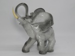 FAIANÇA, uma (1) escultura na tonalidade cinza representando elefante, presas em polímero na tonalidade marfim, sem marca de manufatura aparente, medindo 19,5 cm altura.