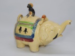 FAIANÇA JAPONESA, um (1) bule modelado na forma de elefante, policromado com predominância da tonalidade amarela, pega da tampa na forma de figura sentada, falta a alça que seria em tresse de fibra vegetal, marcado na base H dentro de losango e flor de cerejeira, possui o craquelê característico do envelhecimento de toda a faiança, medindo 22 cm comprimento.