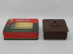 DIVERSOS, duas (2) caixas em metal (folha de flandres): 1 com propaganda da Coca-Cola, visor em polímero, incolor e translúcido, medindo 19,5 x 16,5 x 5,5 cm; 1 com patina marrom, pés esféricos, tampa vazada, medindo 14 x 14 x 8,5 cm.
