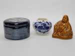 FAIANÇA, três (3) itens: 1 deus Hotei (um dos sete deuses do Shichi Fukujin no Xintoísmo), tonalidade caramelo, medindo 9,5 cm altura; 1 pote com tampa, cilíndrico, tampa com ornamentação floral policromada sobre fundo preto metalizado que lembra hematita, medindo 10,5 cm diâmetro; 1 vaso bojudo, ornamentação floral pintada a mão na técnica blue and white, assinado S. PEREIRA, MG, 95, medindo 6 cm altura.