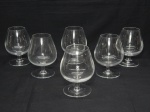 DEMI CRISTAL, seis (6) taças de pé baixo para conhaque, incolores e translúcidas, bojudas, fuste cilíndrico, base em bolacha, medindo 12,5 cm altura. Uma com bicado.
