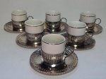 METAL PRATEADO E PORCELANA, doze (12) itens: 6 xícaras para café, cilíndricas na tonalidade branca, arremates com frisos prateados; monture e pures em metal, sem marca de manufatura aparente; acompanha 6 colheres para café, manufatura BELLINI PRATA 90, lacradas e sem uso, medindo 12 cm comprimento.