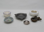 DIVERSOS, seis (6) cinzeiros distintos: 1 em metal prateado com propaganda do CAN (Correio Aéreo Nacional) da Força Aérea Brasileira, medindo 6 cm diâmetro; 1 em pewter no padrão inglês Georgiano, puncionado JS-MG (JOHN SOMERS, em 1956 o oficial inglês, nascido em Birmingham, John Somers, radicou-se no Brasil e começou a trabalhar como antiquário no Largo do Boticário, RJ; paralelamente abriu uma oficina de restauro e reproduções de itens antigos em São João Del Rei, MG; em 1968 abriu a empresa John Somers Ltda em São João Del Rei para produzir objetos em estanho e cópias de mobiliário inglês; em 1994 vendeu a empresa que ainda se encontra em funcionamento), medindo 13,5 cm diâmetro; 1 em bronze, medindo 10 x 9 cm; 1 em faiança italiana com singela ornamentação floral policromada pintada a mão, souvenir de Albergo Bologna, Roma, marca ETRURIA, Perúgia, medindo 10 cm diâmetro; 1 com propaganda do LES HOTELS ASTIR, Grécia, marca de manufatura no alfabeto Grego, medindo 12 cm diâmetro; 1 com decoração vegetalista, pintado a mão na técnica blue and white, manufatura ETIENNE (Itaipava, Petrópolis, RJ), medindo 9,5 cm diâmetro, possui bicadinho na borda.