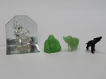 VIDRO, quatro (4) esculturas representando elefantes e buda: 1 incolor e translúcido com base espelhada; 1 na tonalidade preta com quebrados e perdas; 2 na tonalidade jade com pequenas perdas, medindo o maior 7 cm.