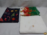 Lote composto de duas toalhas de mesa e um tapete com motivos natalinos. Medindo a toalha branca 240cm x 140cm. Possui marcas de guardado.