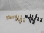 Jogo de xadrez incompleto com peças em pedra esculpida.