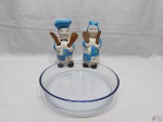 Lote composto de travessa redonda funda em vidro temperado com 2 suportes na forma de cozinheiros em porcelana com colheres de pau. Medindo a travessa 26cm de diâmetro x 5,5cm de altura