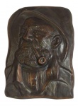 Escultura. Placa em metal representando um MARUJO fumando CACHIMBO. Altura aproximada: 22,5 cm. Possui dois furos na parte superior que permite a sua fixação na parede ou em outra superfície.