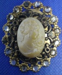 ANTIGO BROCHE - CAMAFEU CONFECCIONADO ARTESANALMENTE EM METAL DOURADO E RESINA, CONTEM ALGUMAS PEDRAS NÃO IDENTIFICADAS PEÇA COM 4,8 x 3,8 cm E COM 12,2 g