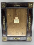 Porta Retrato de Jacarandá adornado por elementos decorativos representando elementos florais em metal. Medidas 32x26 cm. Falhas no acabamento da madeira.