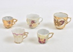 Conjunto de 5 xícaras de café para coleção, de fina porcelana com apliques e desenhos em acentuado relevo e destaque para farta douração. Ausencia dos pires e 1 c/ fio de cabelo e borda bicada