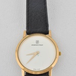 Relógio de pulso Amsterdam Sauer, mostrador redondo com fundo branco, ponteiros e caixa dourados. Pulseira de couro preto. Caixa 3,3 cm diametro. Parado, sem garantias. Caixa 3,5x2,5 cm