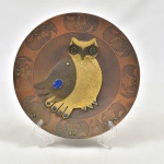 Belíssimo prato de parede, em cobre, borda decorada com corujas e ao centro grande coruja em folhas de flandres com pedras sul-americanas. Assinada Gómez, Chile. Diam 25cm