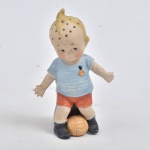 Boneco estilo Kewpie jogando futebol, raro saleiro e paliteiro em porcelana policromada. Alemanha. Obs.: Braço  esquerdo e pescoço colados. (11 cm)