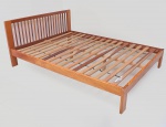 Cama de casal de madeira no tom canela, cabeceira com hastes torneadas. Medida do estrado 176x140 cm