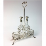 Belo galheteiro em prata de lei fundida, vazada e contrastada de estilo e época Art Nouveau. Recipientes em cristal. Europa, cerca de 1900. (Uma garrafa bicada na base). 34 x 24 x 08 cm.