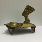 EGITO - Antigo e belo cinzeiro "NARFETITI " em bronze, apoiado por 4 pés. Dimensões: 12 cm x 14 cm x 11 cm.