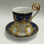 Bela xícara em porcelana, de coleção, apoiada por três pés, decorada com cenas gregas  em azul, preto e realces pintado à Ouro. Dimensões: 9 cm altura.