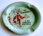Antigo e raro cinzeiro - Zé Kilowatt. O seu servidor elétrico - Mascote da Light, criado nos anos 50 - Era astro da revista da Light. Com desenhos animados que orientava as crianças sobre o uso seguro e eficiente da eletricidade - Além de ser brinde para clientes - Marcou época - Metal - Possui marcas do tempo e corrosão. Não prejudicando o personagem - 12 cm de diâmetro.