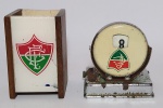 Colecionismo - Antigo e Raro - Lote: Antigo Calendário Permanente em metal, com marcadores de, mês, dia e semana. Representando o Fluminense Futebol F. C. + Porta caneta representando o Clube - OBS: Porta caneta estrutura em madeira e acrílico possui uma rachadura em 1 dos lados do acrílico, não comprometendo a peça - Conforme fotos - Medida maior: 9 x 7 x 6 cm.