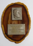 Antigo e raro Souvenir de Brasília - Representando o Ex-Presidente Jucelino Kubitschek, e uma das suas frases famosas: '' Tudo se transforma em alvorada nesta cidade que se abre para o amanhã'' Esfinge em alto relevo, frase com assinatura em metal prateado, sobre pedra Ágata marrom - Medida: 500,00