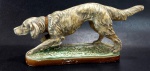 Antiga escultura representando cão de caça manufaturada em estuque policromado. Possui algumas perdas (bicados). Mede 15 cm de altura por 29 cm de comprimento.