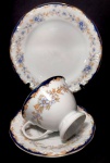 PORCELANA SCHMIDT CLASSIC - Trio para chá e bolo em porcelana decorada por flores e acantos em tons sutis de policromia. Mede 7,5 x 9,5 cm a xícara, 14 cm de diâmetro o píres e 19 cm de diâmetro o prato para bolo.