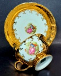 DANIELE MILIONE - Xícara de chá e respectivo pires decorados por cena galante em policromia e farta pintura em ouro. Mede 5,5 x 9,5 cm a xícara e 14,5 cm de diâmetro o pires.