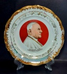 Medalhão decorativo em porcelana representando a imagem do Papa João XXIII (1881 - 1963) que foi pontifice máximo da igreja católica de 1958 até seu falecimento. Possui borda com volutas em relevo e pintura em ouro (com alguns pontos de desgaste). Mede 24,5 cm de diâmetro.